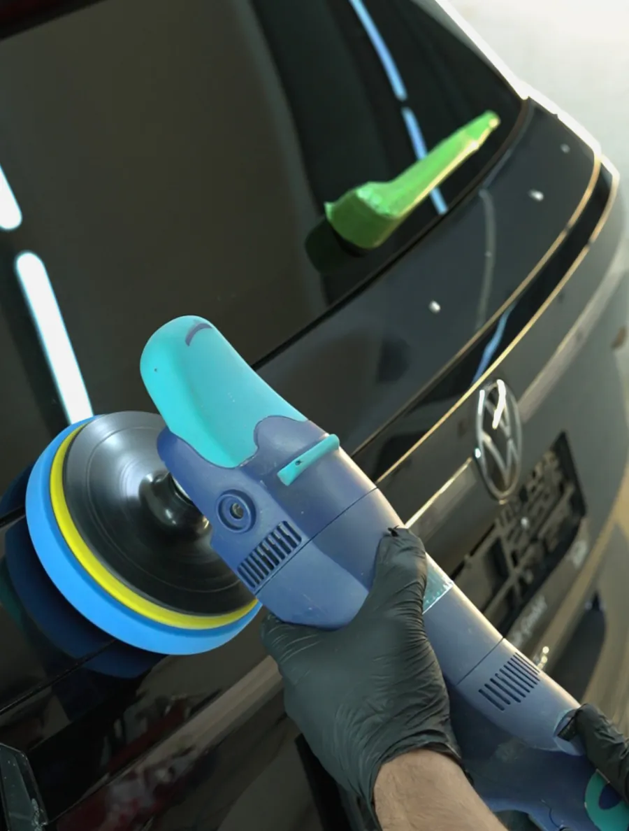 Poliermaschine mit Polierschwamm am Heck eines schwarzen Fahrzeugs